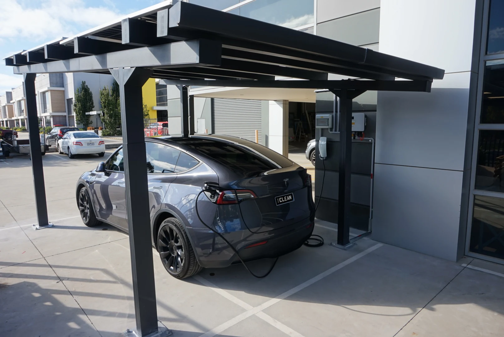 The single carport beside the building, with an electric vehicle connected to the charger.