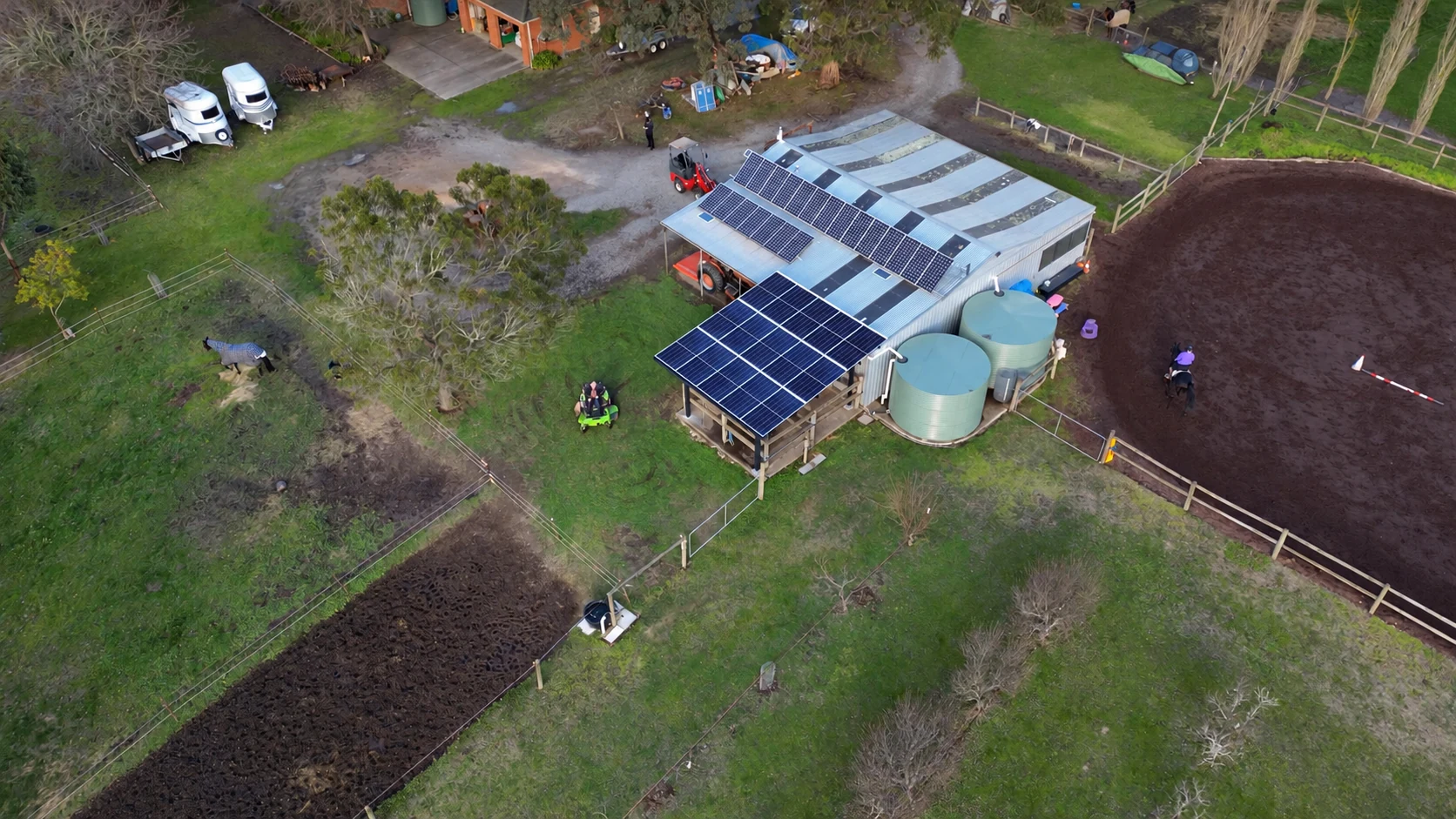 Aerial view: the carport canopy is beside the outbuilding, which has a separate rooftop array.